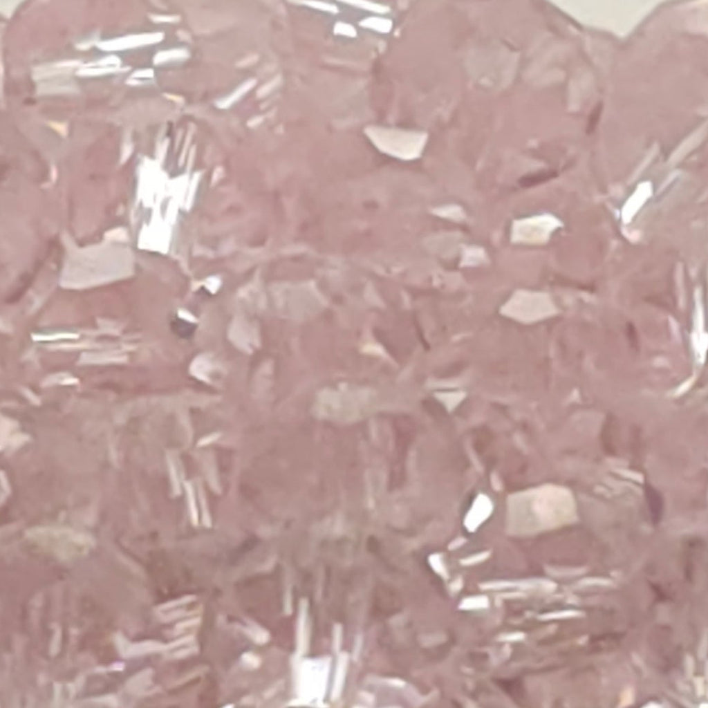 Pink faceted glass beads piled in a shallow black dish against a plain light gray background.