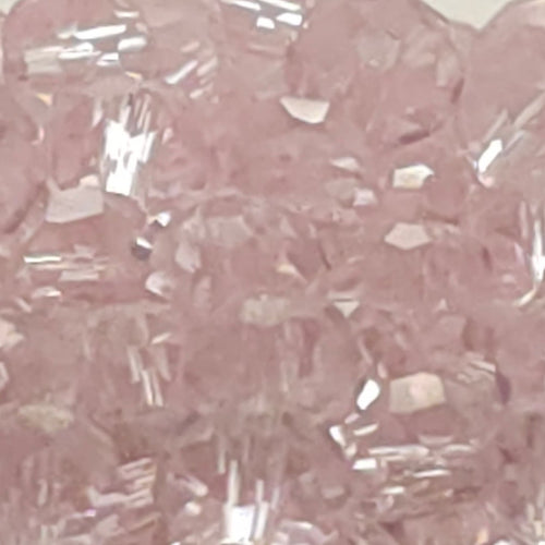 Pink faceted glass beads piled in a shallow black dish against a plain light gray background.
