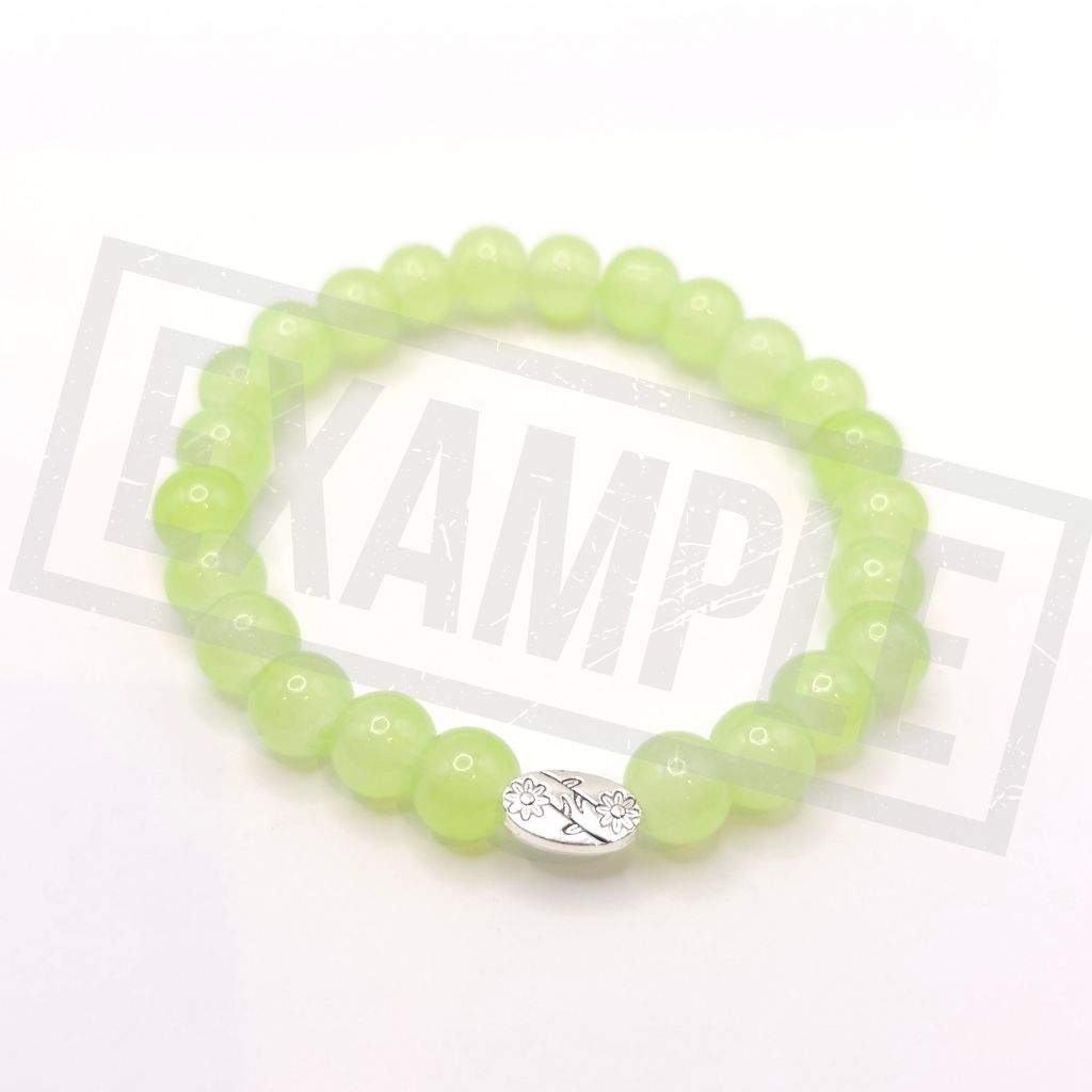 A beaded stretch bracelet made of apple green beads with a silver-toned oval charm, shown on a white background.