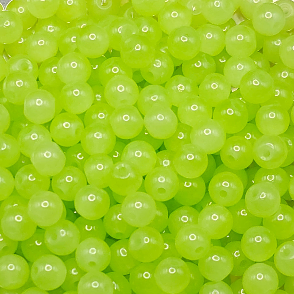A close-up pile of translucent lime green round beads with holes, filling the entire frame.