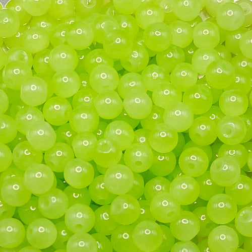 A close-up pile of translucent lime green round beads with holes, filling the entire frame.
