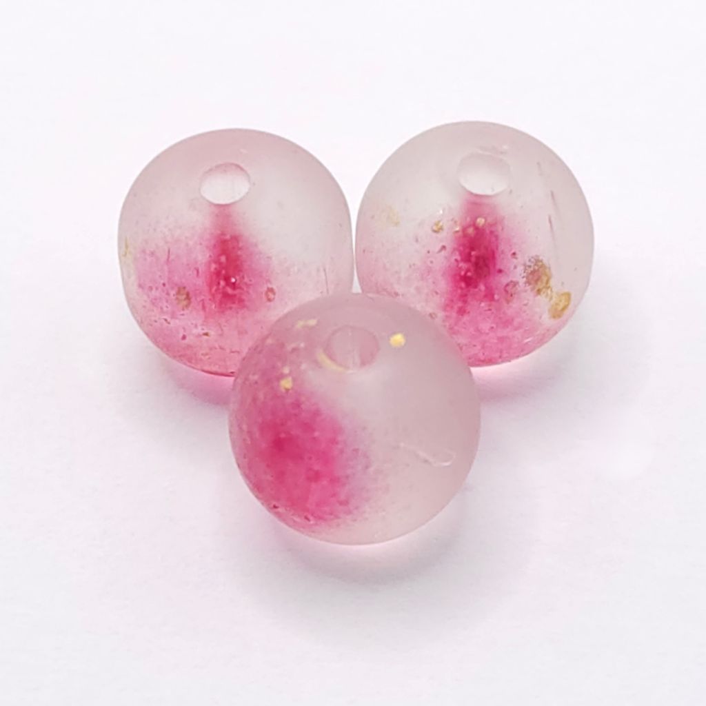 Three round translucent berry-purple beads with embedded pink glitter and small gold flecks, arranged on a plain white background.
