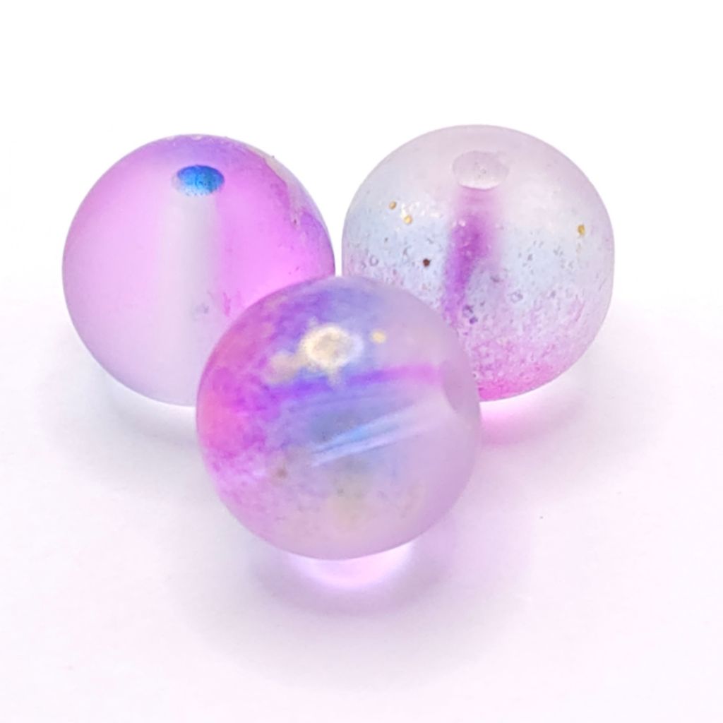 Three translucent lavender and purple acrylic beads with iridescent glitter and small gold flecks, displayed on a clean white background.