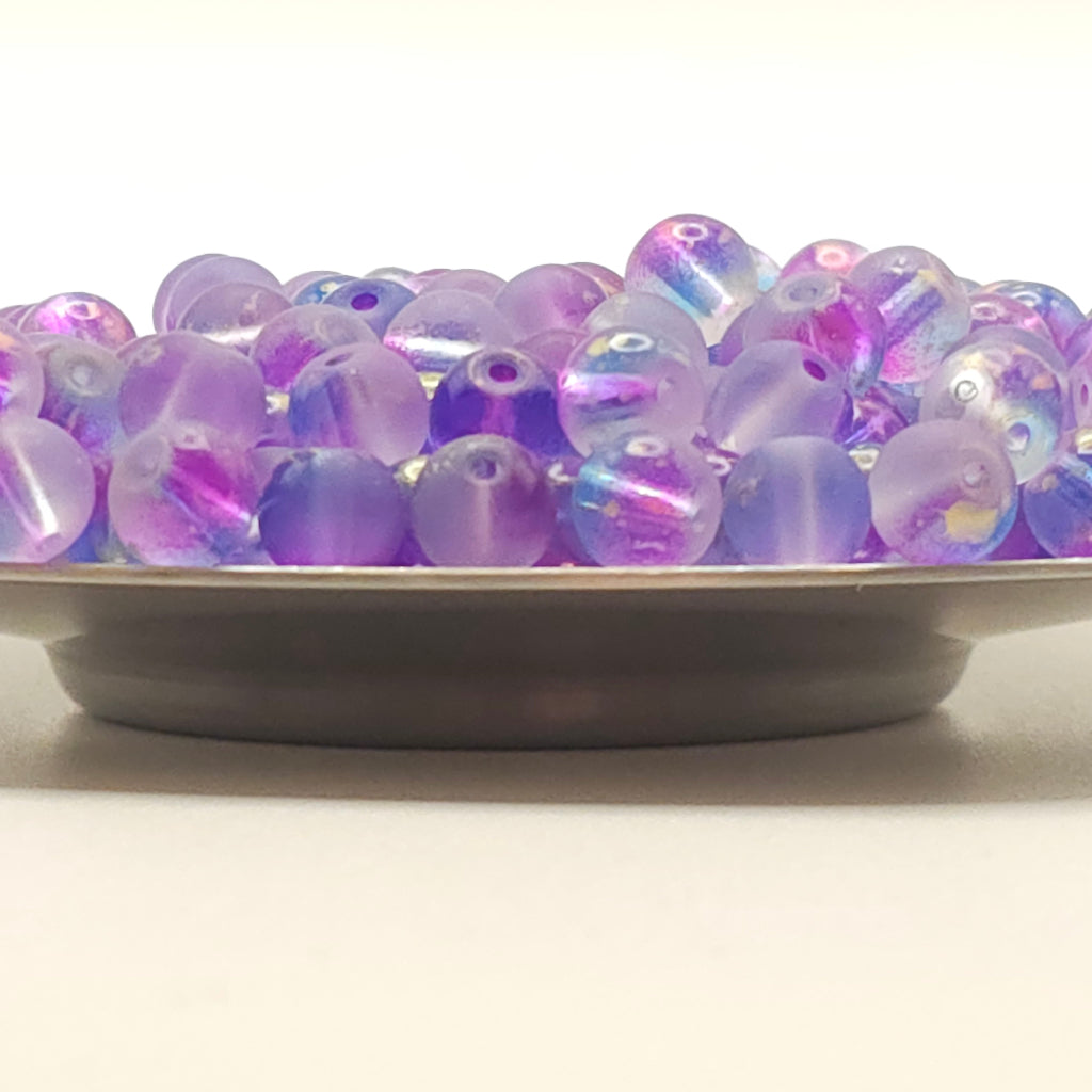 A close-up of a decorative wall light featuring a vertical column of translucent purple and lavender iridescent beads on a dark metal frame against a plain off-white wall.