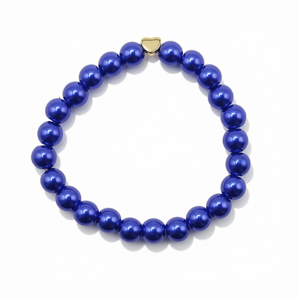 A beaded stretch bracelet made of glossy, deep blue pearlised glass beads with a small gold heart-shaped charm, displayed on a clean white background.