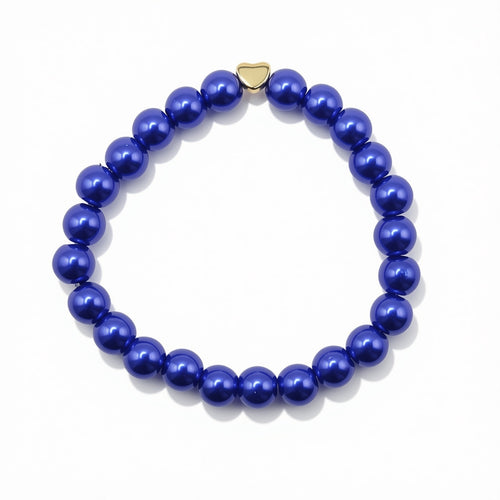 A beaded stretch bracelet made of glossy, deep blue pearlised glass beads with a small gold heart-shaped charm, displayed on a clean white background.