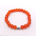 A beaded stretch bracelet made of glossy round orange beads with a textured silver metal accent charm in the center, shown on a plain white background.