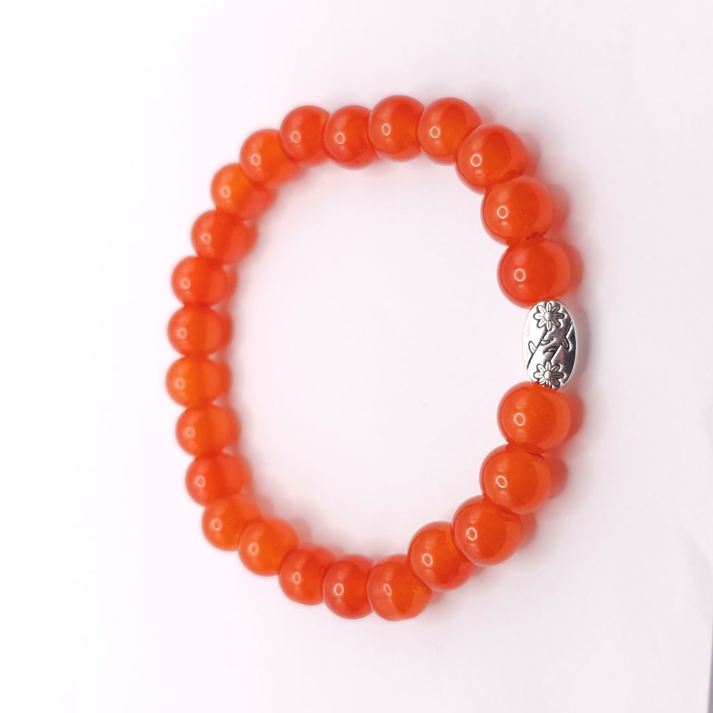 A beaded stretch bracelet made of glossy round orange beads with a textured silver metal accent charm in the center, shown on a plain white background.