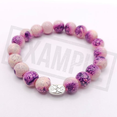 A beaded stretch bracelet with alternating pink and purple marbled beads, featuring a silver-toned oval charm, displayed on a white background.