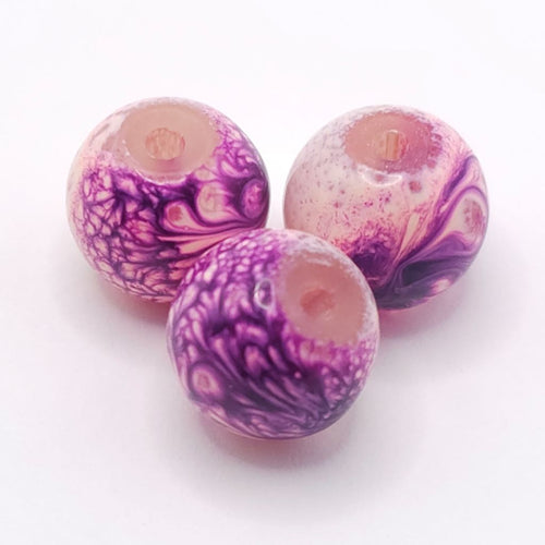 Three round glass beads with a marbled swirl pattern of purple, pink, and white, displayed on a clean white background.