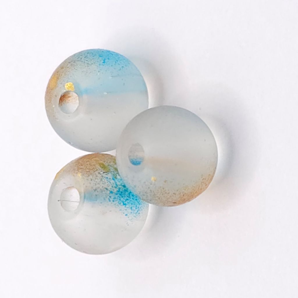 Three round translucent beads with a frosted white base, featuring swirls of light blue, fine gold glitter, and tiny speckles, arranged on a white background.