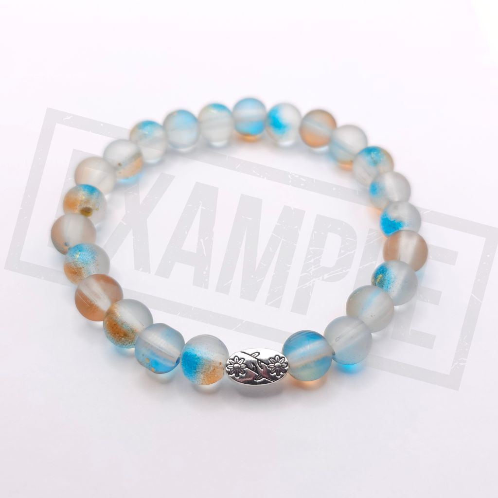 A beaded stretch bracelet featuring round marbled beads in shades of light blue, white, and soft peach, with a small silver-toned decorative bead at the center, displayed on a white background.