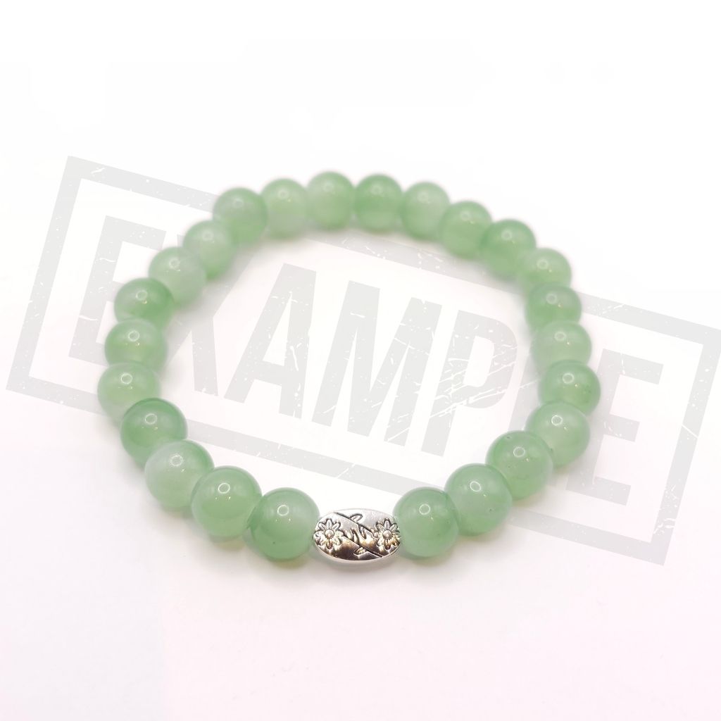 A emerald green beaded bracelet with a silver-toned dragon charm, displayed on a white background.