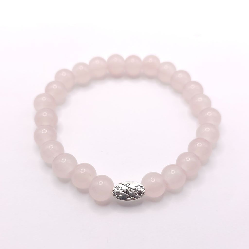 A pink stone beaded bracelet with a small silver-toned decorative charm, displayed on a clean white background.