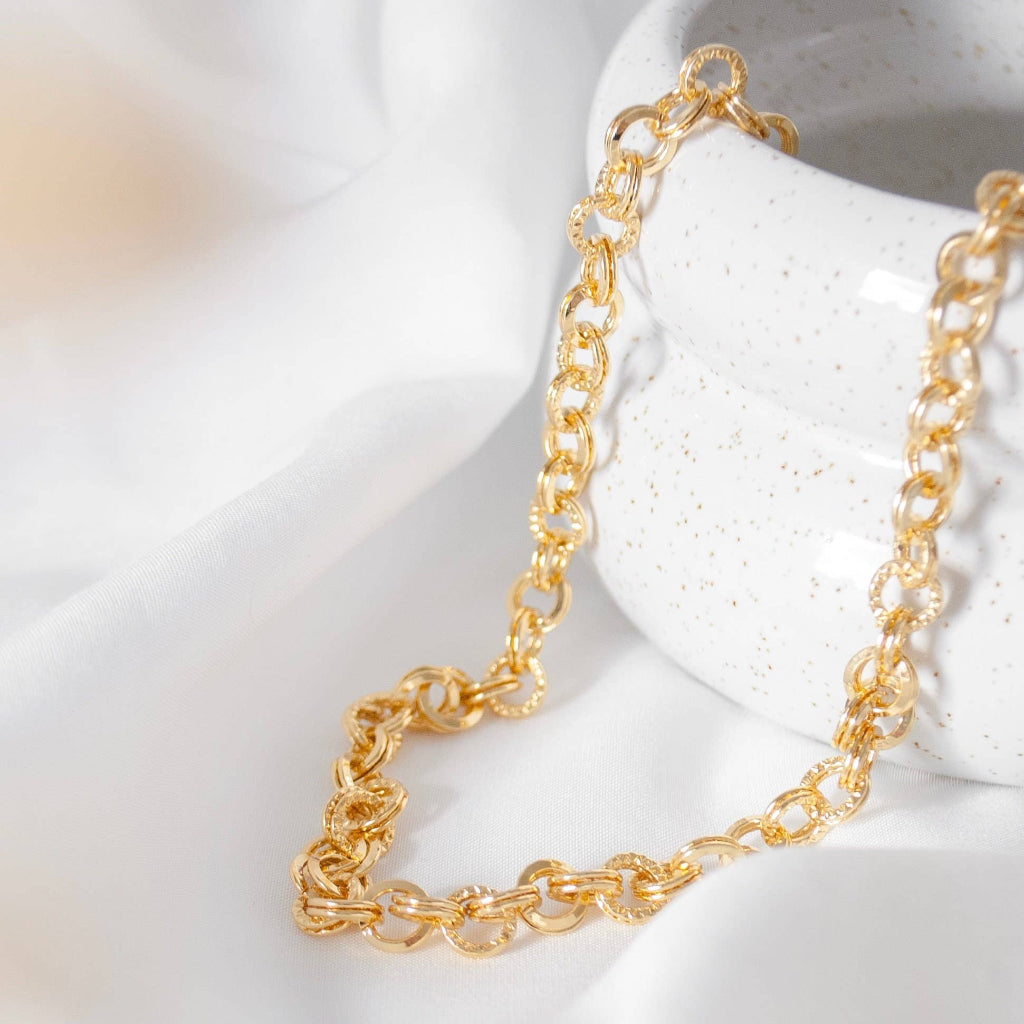 Gold chain bracelet on a white stone surface