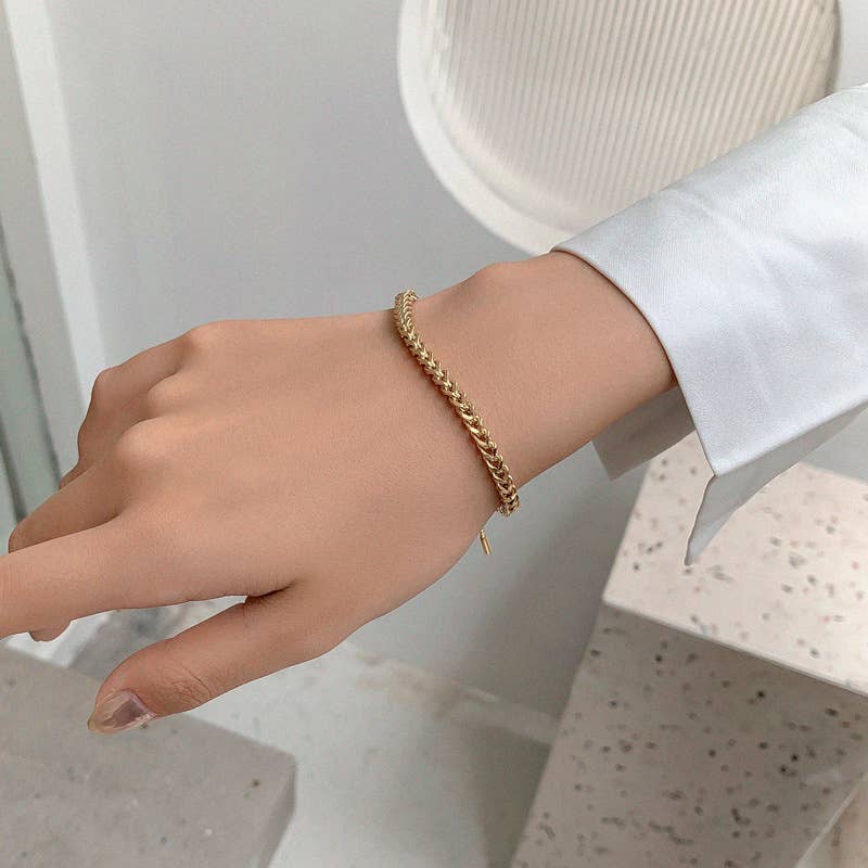 Gold bracelet on a wrist with a neutral background