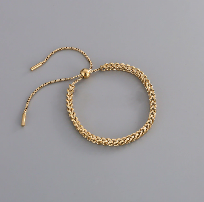 Gold chain bracelet on a grey background