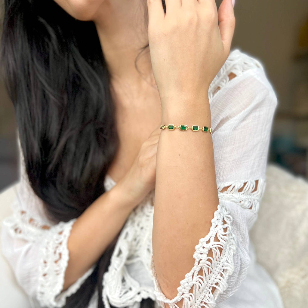 Person wearing a bracelet with green stones on a blurred background