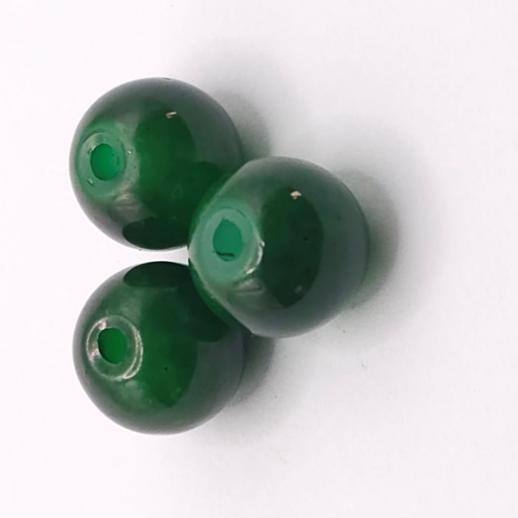 Three glossy green glass beads with central holes, arranged on a plain white background.