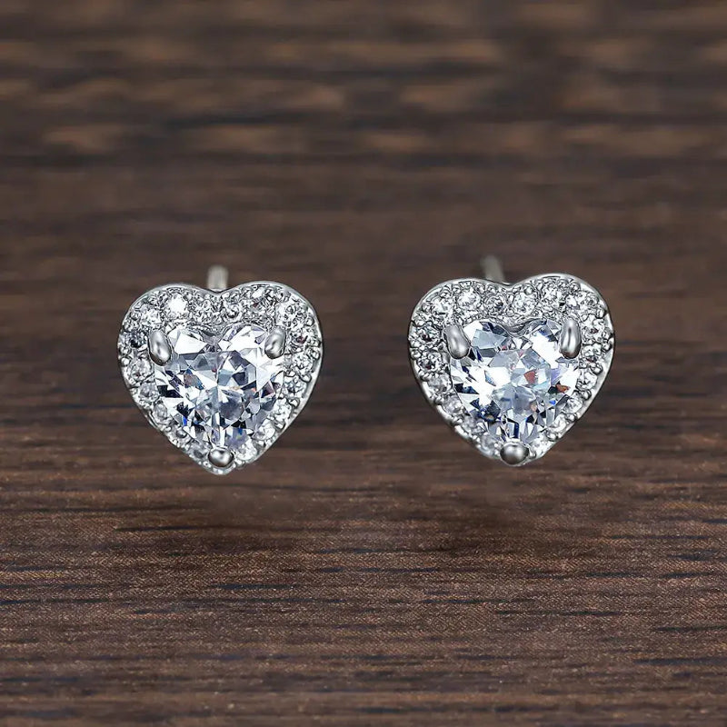 Heart-shaped diamond earrings on a wooden surface