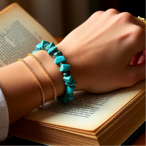 Hand wearing a turquoise bracelet on an open book
