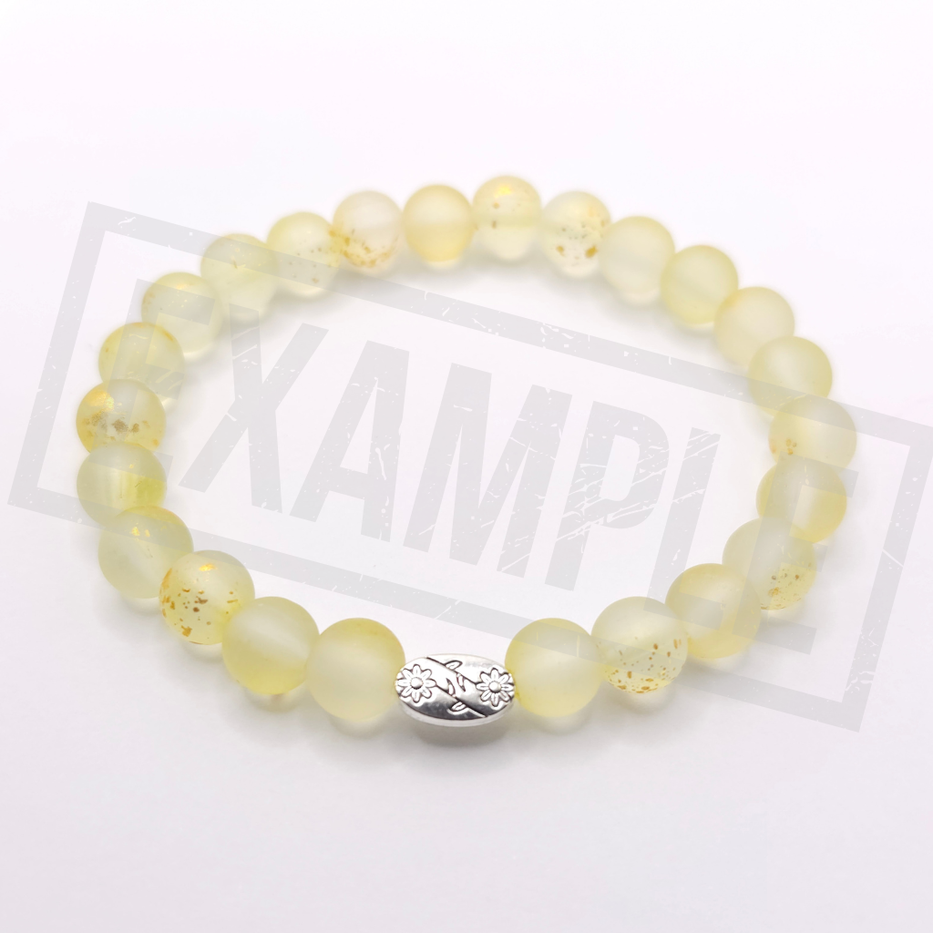 A beaded stretch bracelet made of lemon yellow translucent round beads with a few containing tiny gold flecks, featuring a silver-toned fish charm in the center. The bracelet is displayed on a white background.