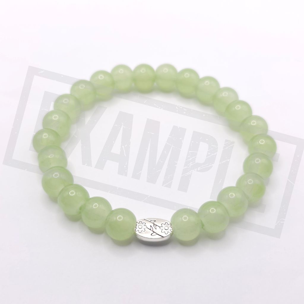 A light aventurine green beaded bracelet with a silver oval charm in the center, displayed on a white background.