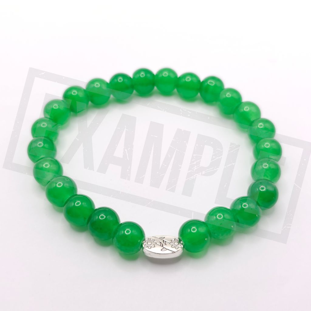 A light green beaded bracelet made of smooth, polished round beads with a small silver-toned oval charm featuring a floral design, displayed on a white background.