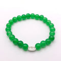 A green beaded stretch bracelet with a polished silver-toned oval charm in the center, displayed on a clean white background.
