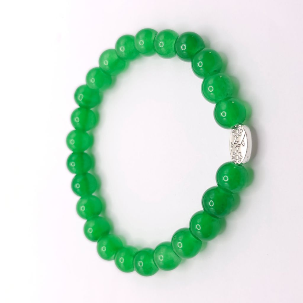 A green beaded stretch bracelet with a polished silver-toned oval charm in the center, displayed on a clean white background.
