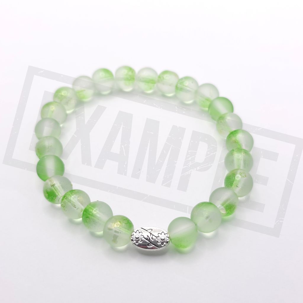 A beaded stretch bracelet made of translucent light lime green round beads with a textured silver accent bead, displayed on a white background