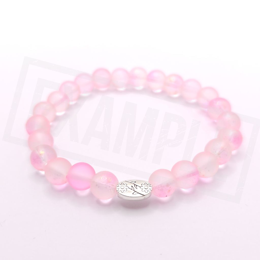 A pink beaded stretch bracelet made of translucent round beads with a small silver oval charm in the center, photographed on a white background.