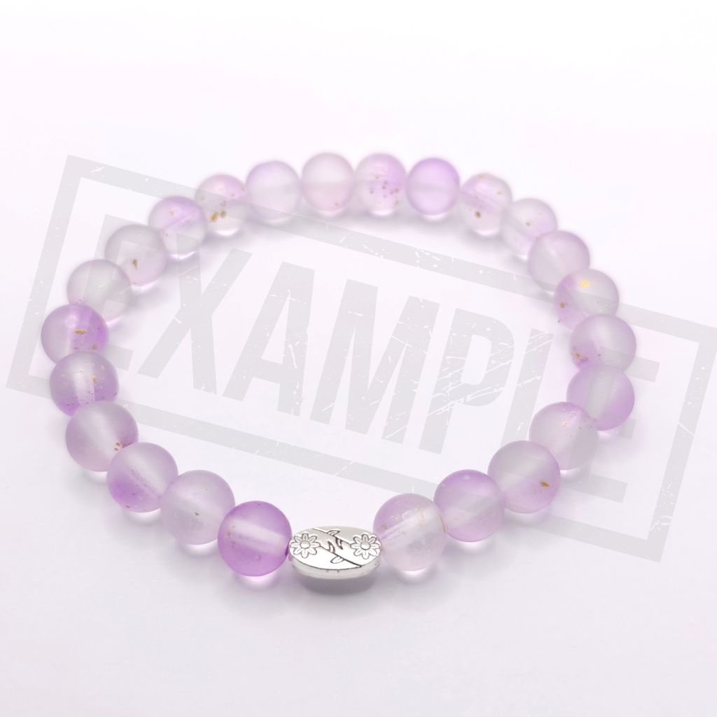 A beaded stretch bracelet made of translucent light purple beads with a small silver oval charm, shown on a white background.