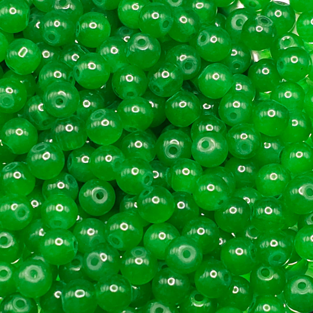 A close-up pile of bright green translucent round beads with central holes, filling the entire frame.