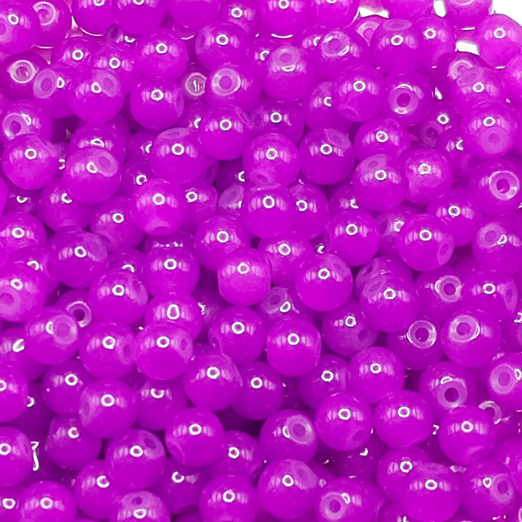A close-up pile of small, round, translucent purple beads with a glossy finish.