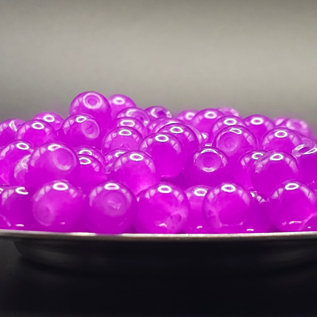 A close-up of glossy translucent purple boba pearls piled in a bowl against a dark gray background.
