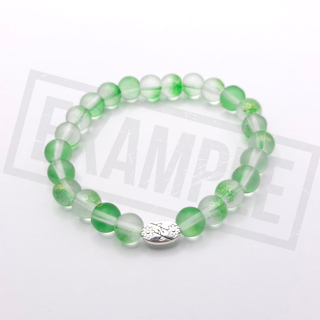 A beaded stretch bracelet made of translucent Lime green and white round beads with a textured silver oval charm, displayed on a white background