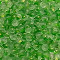 A close-up pile of translucent green glass beads with a frosted finish and small gold glitter flecks inside.