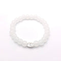 A white beaded stretch bracelet with a silver oval charm featuring a floral design, shown on a plain white background.