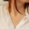 Necklace with a heart-shaped pendant worn by a person in a white shirt.