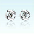 Pair of silver earrings with clear gemstones on a light blue background