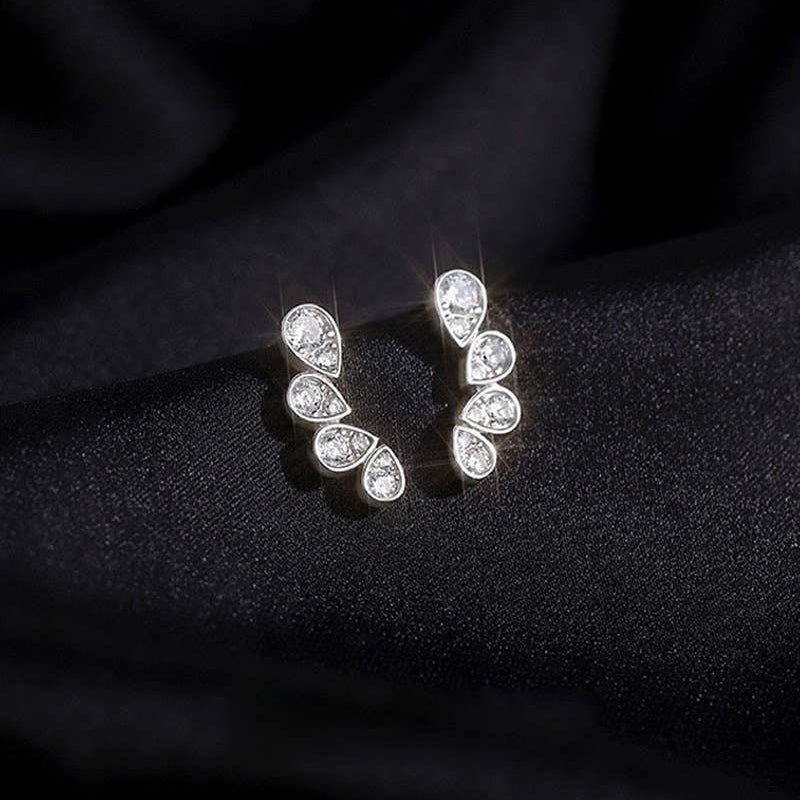 Pair of silver earrings with teardrop-shaped gemstones on a black fabric background