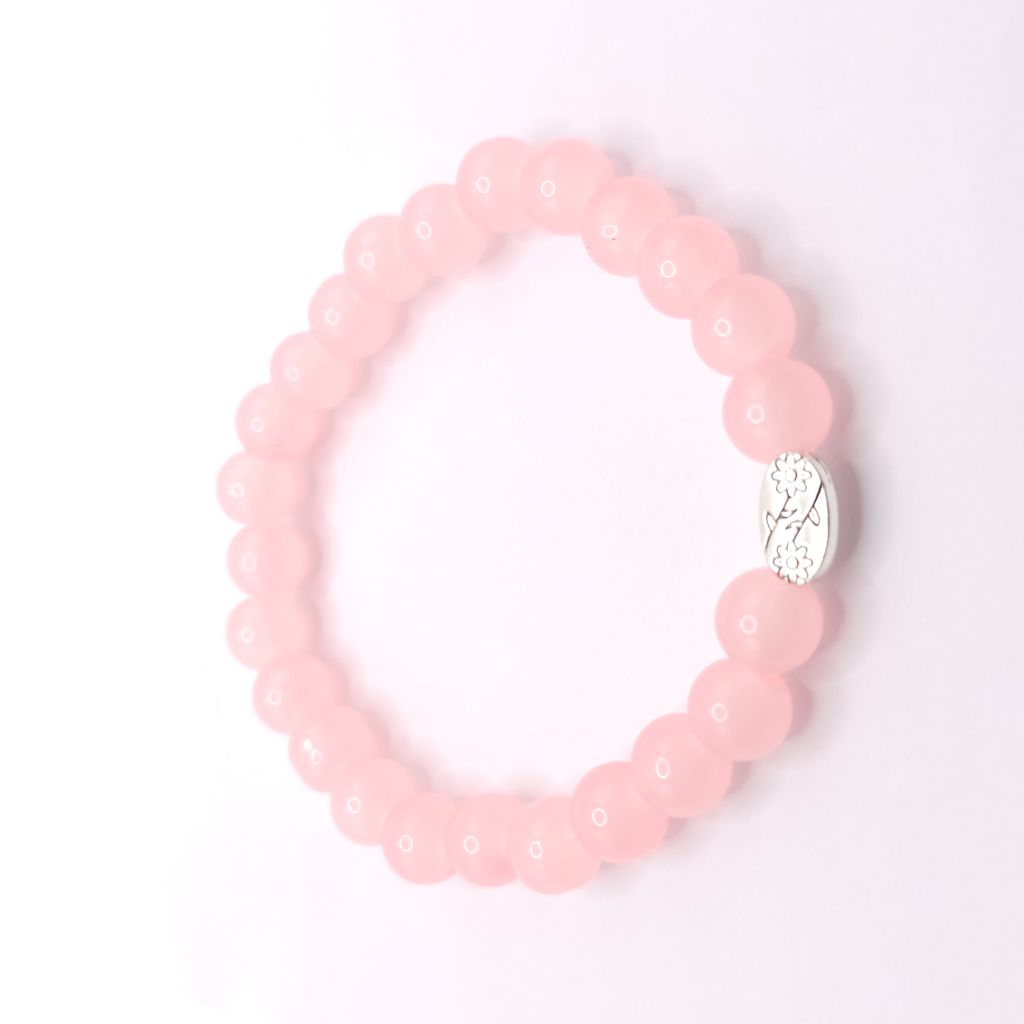 A pink beaded stretch bracelet with a small silver oval charm featuring a metal charm, displayed on a clean white background.