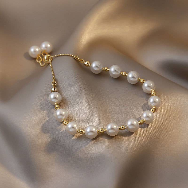 Pearl bracelet with gold accents on a soft fabric background