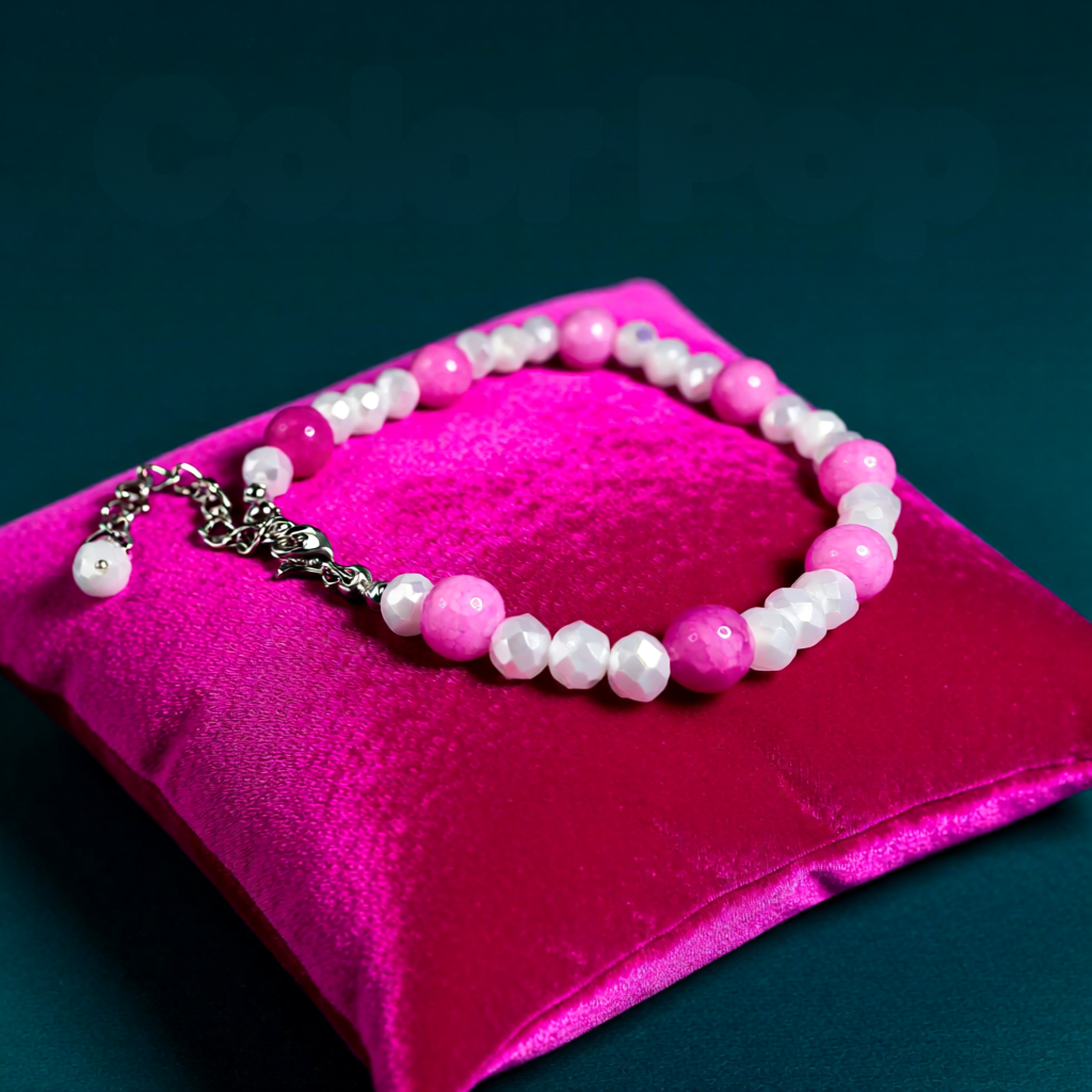 Pink and white beaded bracelet on a pink pillow with a dark blue background