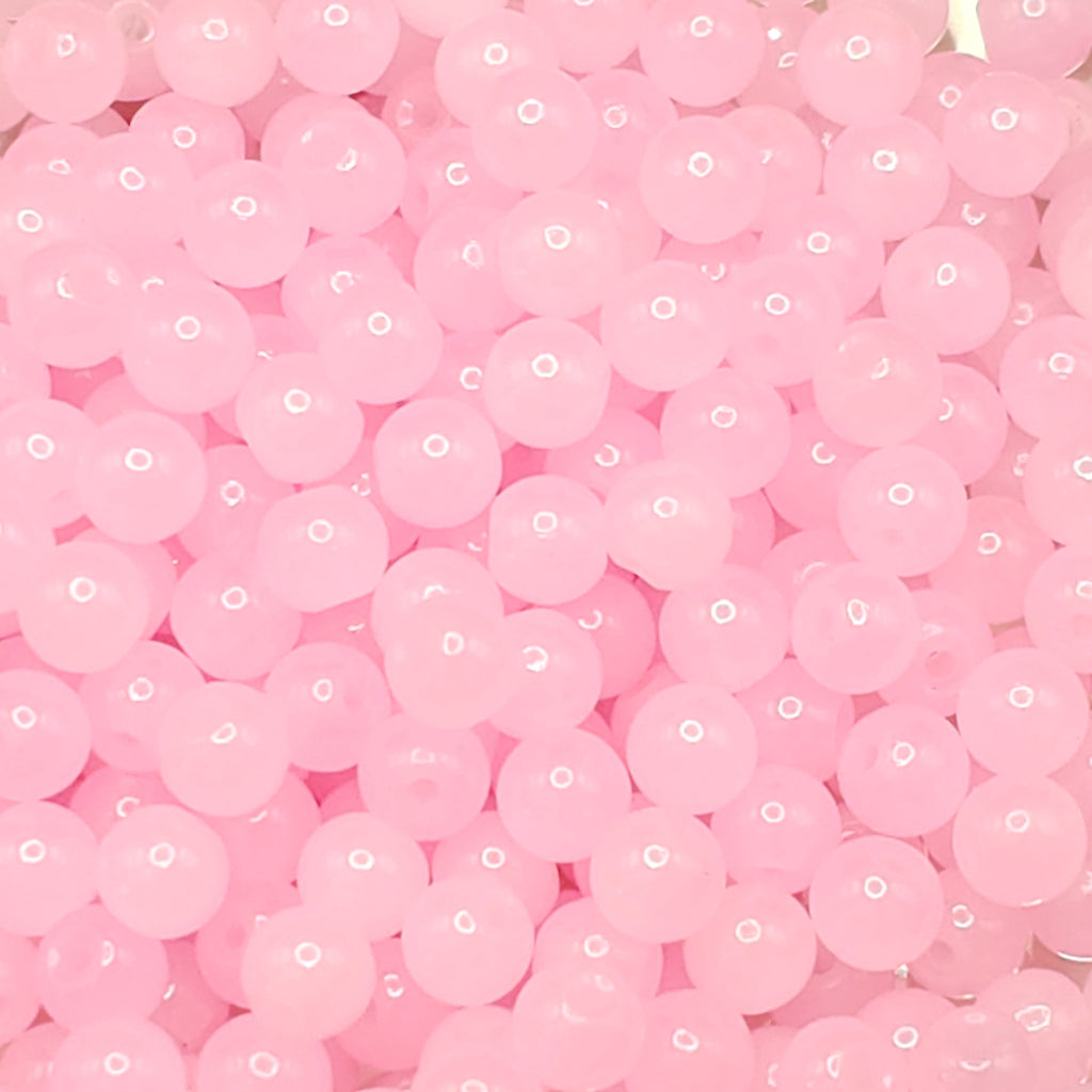 A close-up pile of small, translucent pink round beads with white highlights.