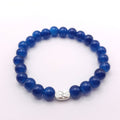 A beaded stretch bracelet made of glossy dark blue beads with a small silver-toned decorative charm, shown on a plain white background.