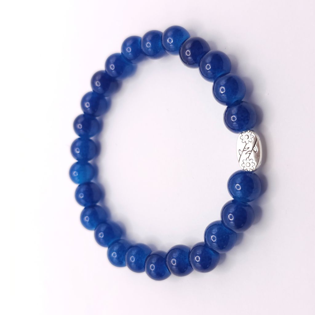 A beaded stretch bracelet made of glossy dark blue beads with a small silver-toned decorative charm, shown on a plain white background.