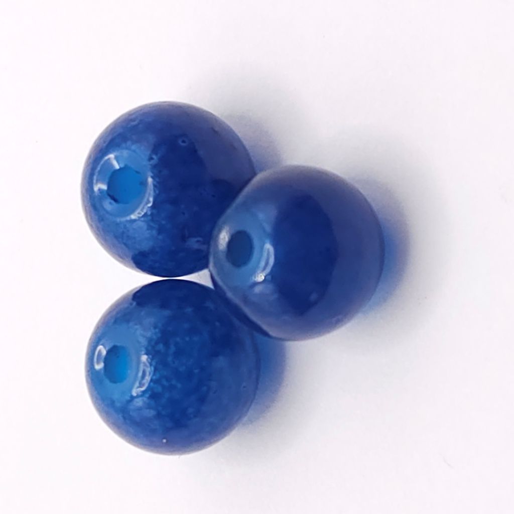 Three glossy sapphire blue glass beads with a central hole, arranged on a plain white background.