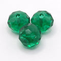 Three faceted green glass beads with a central hole, arranged on a plain white background.